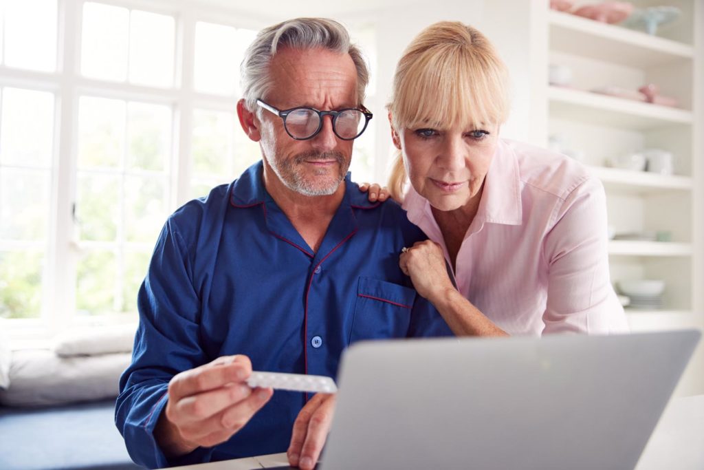 Serious Mature Couple At Home Looking Up Information About Medication Online Using Laptop