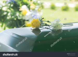 stock-photo-a-closeup-of-flowers-atop-a-funeral-casket-outdoors