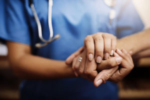 a medical worker holding hands with an older patient