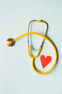 Close-up of a stethoscope sitting next to a paper cutout heart
