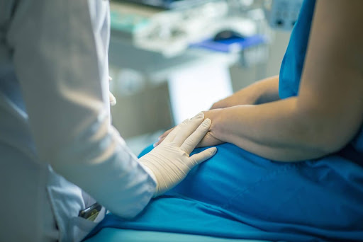 Close-up of a doctor’s hand touching a patient’s arm
