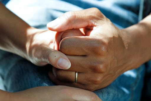 Two people clasping their hands tightly 