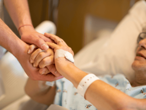 A hospital patient holding hands with a loved one
