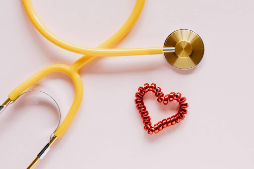 Close-up of a yellow stethoscope next to a red heart