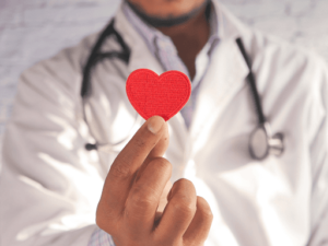 A doctor holding a small red paper heart